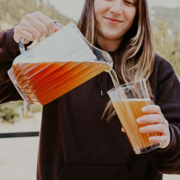 Female pouring beer jug in to pint glass on a sunny day