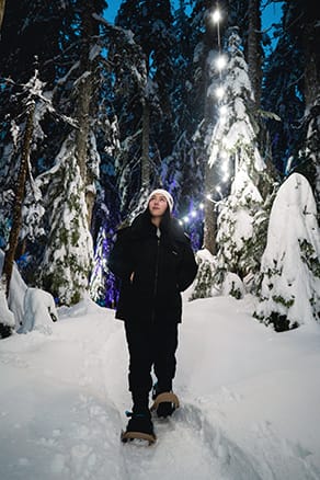 Female on snowshoes under fairy lights